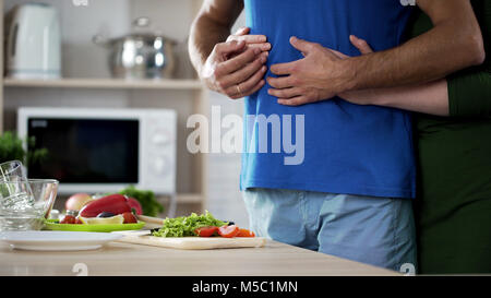 Young couple hugging during dinner preparation in kitchen, care and support, stock footage Stock Photo
