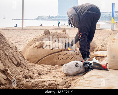 Man is making a dragon sand sculpture on the Sant Miguel beach in Barcelona Stock Photo
