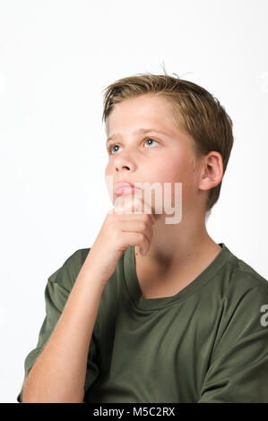 Side head and shoulders view of a young male teenager in front of white background with hand on chin looks up. Stock Photo