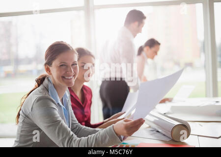 Portrait of smiling young female architects with paperwork at table in office Stock Photo