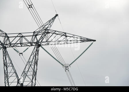 Portion of top of waist-type electricity pylon/transmission tower against an overcast sky. Stock Photo