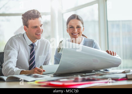Young architects working together on blueprint at desk in office Stock Photo