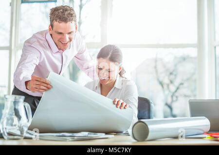Young architects looking at blueprint at office desk Stock Photo