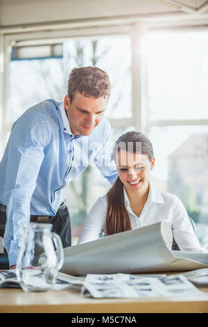 Young architects looking at blueprint at office desk Stock Photo
