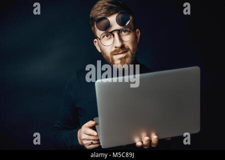 Portrait of handsome brunette bearded man working in office using silver laptop Stock Photo