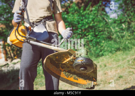 Man Mowing the Grass by using gasoline lawn trimmer Stock Photo
