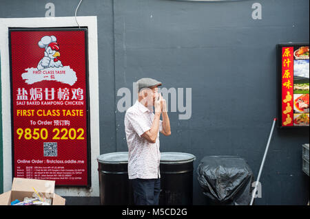 17.12.2017, Singapore, Republic of Singapore, Asia - An elderly man talks on the phone in Singapore's Chinatown district. Stock Photo
