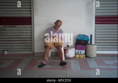 19.02.2018, Singapore, Republic of Singapore, Asia - An elderly man sits on a chair at the Chinatown Complex shopping centre in Singapore's Chinatown  Stock Photo