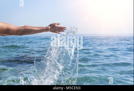 Women's hands do the spray of the sea. Stock Photo