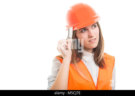Pensive pretty female constructor with credit card looking far away on white background with copyspace Stock Photo