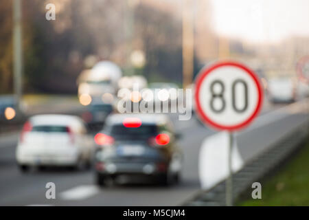 Defocused image of traffic sign showing 80 km/h speed limit on a highway full of cars Stock Photo