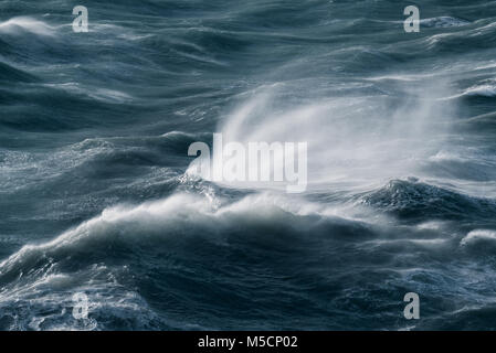 Storm on the sea. Strong wind sculptures the sea and makes shapes of wave splash. Looks like splash has fingers and wave to people. Stock Photo