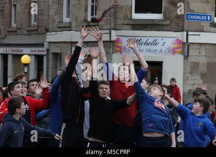 Boys tussle for the leather ball during the annual 'Fastern Eve Handba' event on Jedburgh's High Street in the Scottish Borders. The annual event, which started in the 1700's, involves two teams, the Uppies (residents from the higher part of Jedburgh) and the Doonies (residents from the lower part of Jedburgh) getting the ball to either the top or bottom of the town. The ball, which is made of leather, stuffed with straw and decorated with ribbons is thrown into the crowd to begin the game. Photo credit should read: Andrew Milligan/PA Wire. Stock Photo