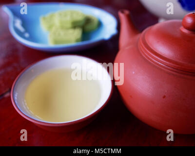 Traditional chinese tea set compose of cup of tea, teapot, and snack on wooden background Stock Photo