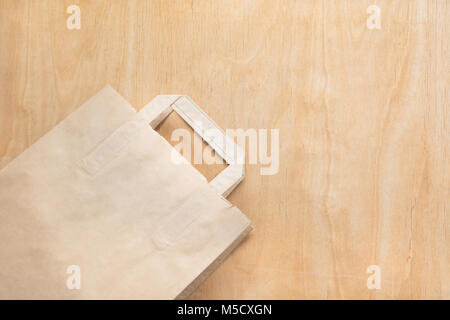 Clean brown kraft paper bag lying on a plywood table. Top view. Stock Photo