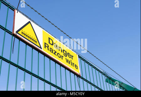 Danger Razor Wire warning sign on top of a security fence in the UK. Stock Photo