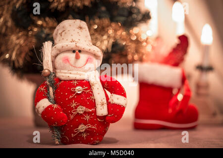 Cute snowman toy - Christmas ornament, with Christmas tree in the background; Stock Photo