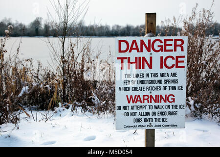 Danger Thin Ice warning sign next to a frozen lake at Neighbridge Country Park near Somerford Keynes in the Costwold Water Park Stock Photo