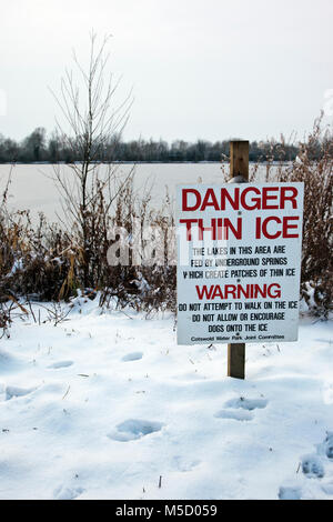 Danger Thin Ice warning sign next to a frozen lake at Neighbridge Country Park near Somerford Keynes in the Costwold Water Park Stock Photo