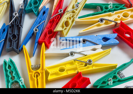 Clothespins of different shapes, sizes and colours scatered across a white background Stock Photo