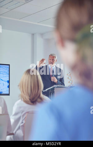 Pharmaceutical businessman explaining medication at podium at conference Stock Photo