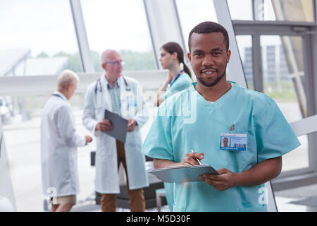 Portrait confident male nurse with clipboard in hospital lobby Stock Photo