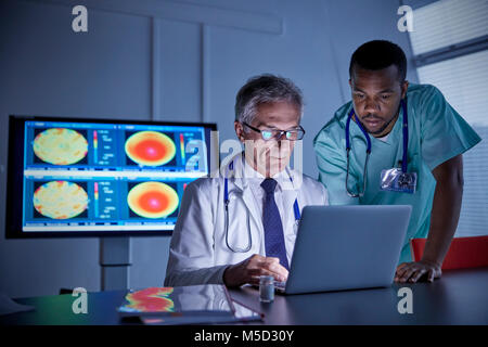 Male surgeon and doctor working at laptop in hospital conference room Stock Photo