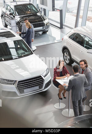 Car sales people meeting at table in car dealership showroom Stock Photo