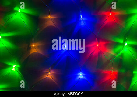 Background image of varicolored lights of a garland in a row on the wall closeup Stock Photo