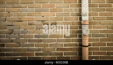 brown brick wall with drainpipe on the right side of frame background Stock Photo