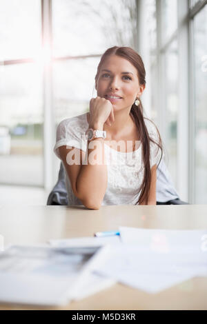 Thoughtful young businesswoman sitting at office desk Stock Photo