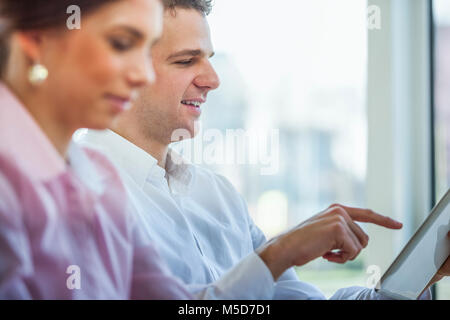 Young businessman using digital tablet with female colleague in foreground Stock Photo