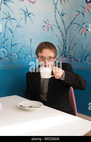 a young happy and confident man with down syndrome sits at a table in a cafe Stock Photo