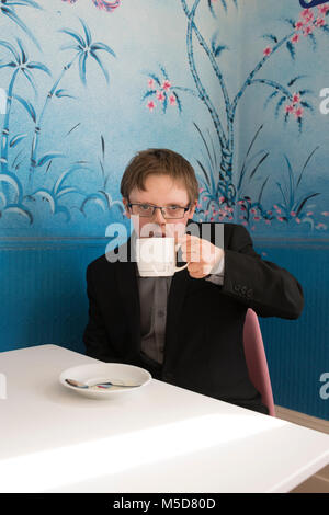 a young happy and confident man with down syndrome sits at a table in a cafe Stock Photo