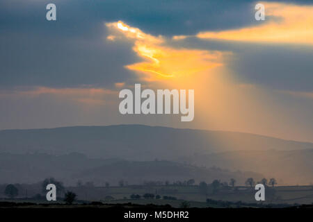 A dramactic lanscape in Wales at sunset as Crepuscular rays break through the clouds to light the rural landscape towards the Clwydian Range or Clwydian Hills in the distance a natural border between Flintshire and Denbighsgure Stock Photo
