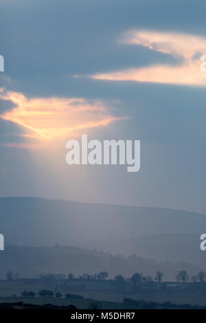 A dramactic lanscape in Wales at sunset as Crepuscular rays break through the clouds to light the rural landscape towards the Clwydian Range or Clwydian Hills in the distance a natural border between Flintshire and Denbighsgure Stock Photo