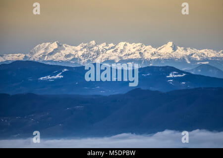 A view of the Slovenian mountain peaks and low clouds during a clear winter day. Stock Photo