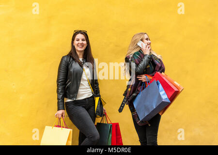 Tired happy teenagers talking on a phone inviting other friends to go and spend money with them Stock Photo