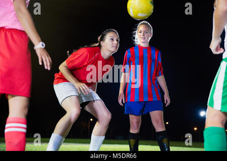 Young female soccer players practicing on field at night, heading the ball Stock Photo