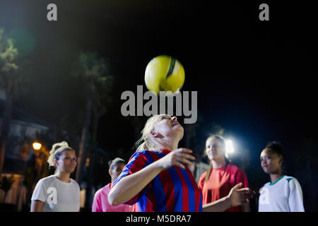 Young female soccer players practicing at night, heading the ball Stock Photo