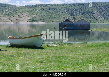old wooden fishing boat reflected on water at a small lake pond