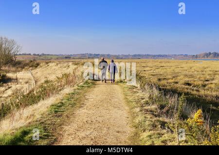 A couple of adults enjoying a countryside walk in rural Suffolk. On the river wall by the River Deben, Waldringfield, Suffolk. Stock Photo