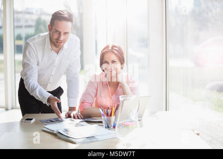 Portrait of confident young business people discussing at desk in office Stock Photo