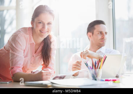 Portrait of confident young businesswoman with male colleague in creative office Stock Photo