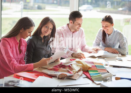 Portrait of young businesswoman with colleagues discussing at desk in creative office Stock Photo