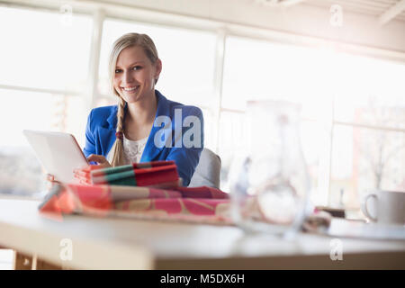 Portrait of confident young businesswoman using digital tablet at desk in creative office Stock Photo