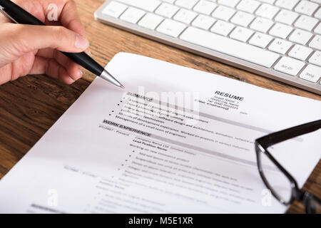 Close-up Of A Job Seeker Review Resume On Wooden Desk At Workplace Stock Photo