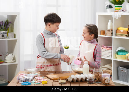 Girl and boy cooking in home kitchen, make the dough for baking, healthy food concept Stock Photo