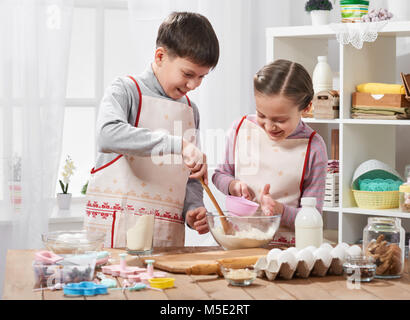 Girl and boy cooking in home kitchen, make the dough for baking, healthy food concept Stock Photo