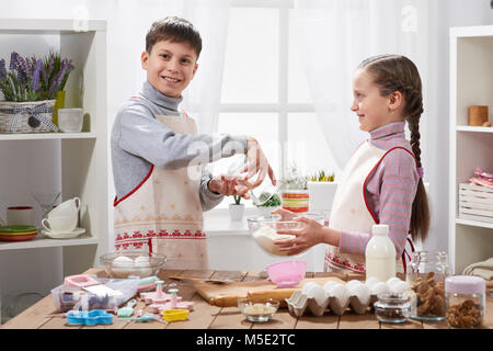 Girl and boy cooking in home kitchen, make the dough for baking, healthy food concept Stock Photo